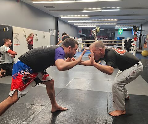 Two adults in a collar tie drilling wrestling takedowns on the mats at Rumble Martial Arts in Keswick.