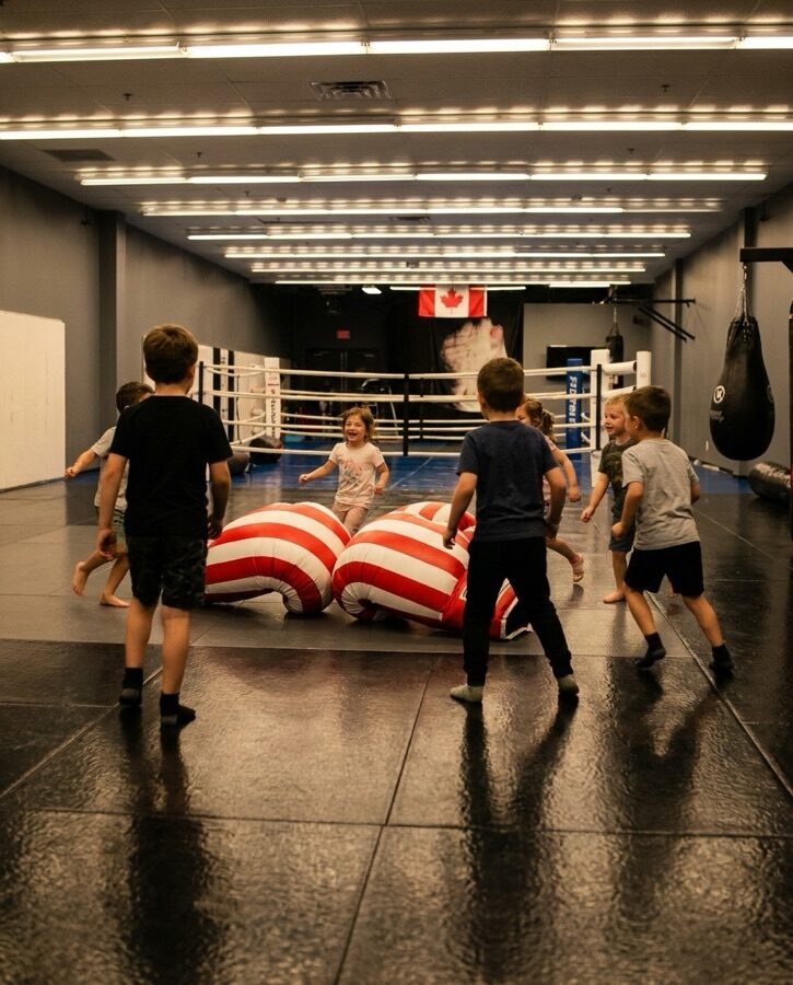 Children playing with oversized jumbo boxing gloves during a camp activity at Rumble Martial Arts.