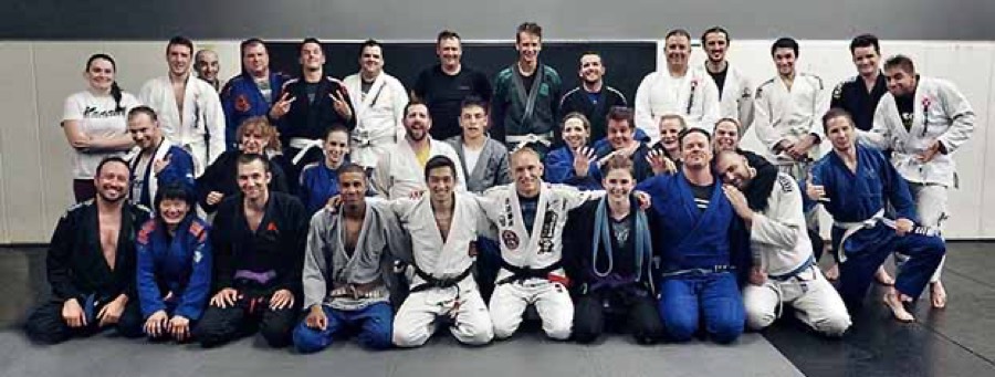 A large Brazilian Jiu-Jitsu class group photo at Rumble Martial Arts, 25-plus students and coaches in gi.