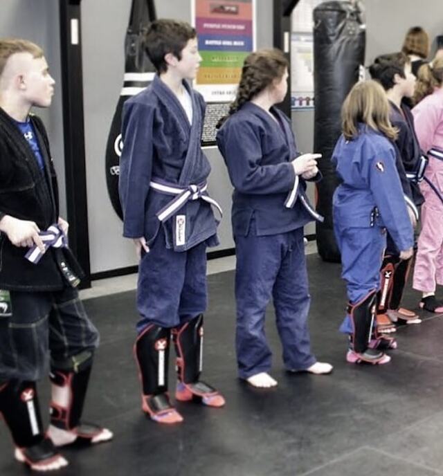 Youth students in gis and shin guards lined up before a Muay Thai class at Rumble Martial Arts in Keswick.